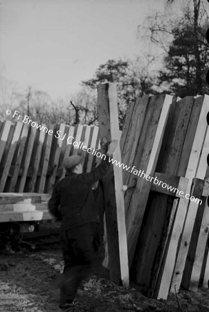 LUMBERING IN LEIX PILE OF WOOD WITH MEN IN FOREGROUND